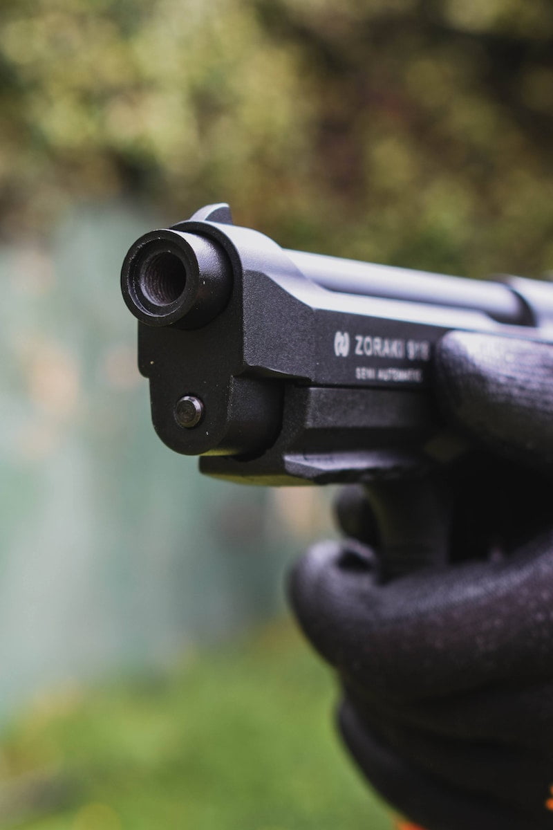 Close-up Photo of Gloved Hands Aiming a Gun