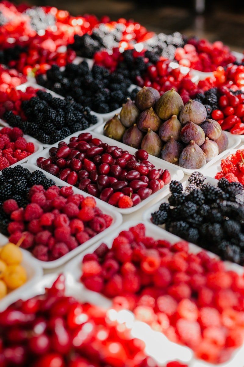 From above of assorted ripe blackberries figs raspberries and fruits of dog rose at counter