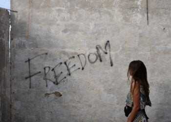 woman in black and white tank top leaning on wall