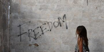 woman in black and white tank top leaning on wall